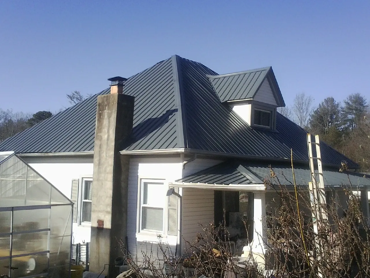 Dark blue standing seam metal roof on a white farmhouse with dormer — Slate & Tile Roof Repair by Roofing Brothers in Oakley